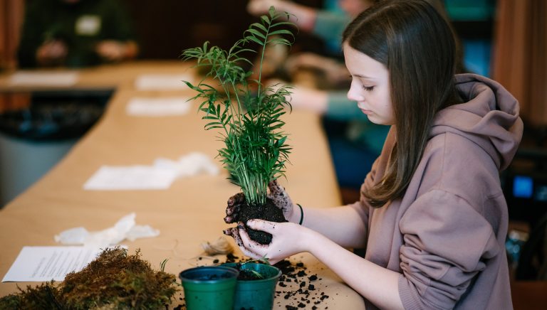 Student holding small unpotted palm plant.