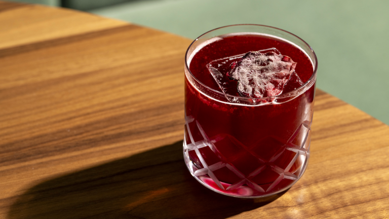 Closeup of deep red drink in a low cut-glass tumbler.