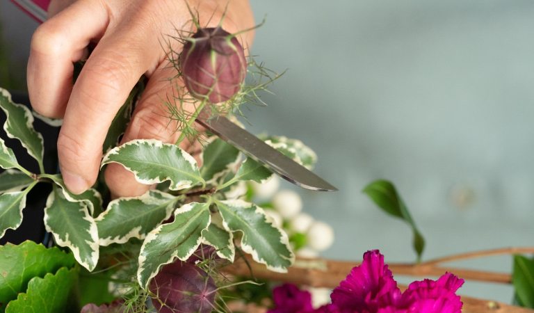 A person cutting a floral display.