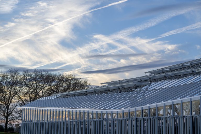 Roof of a large conservatory with vents open against a bright blue sky