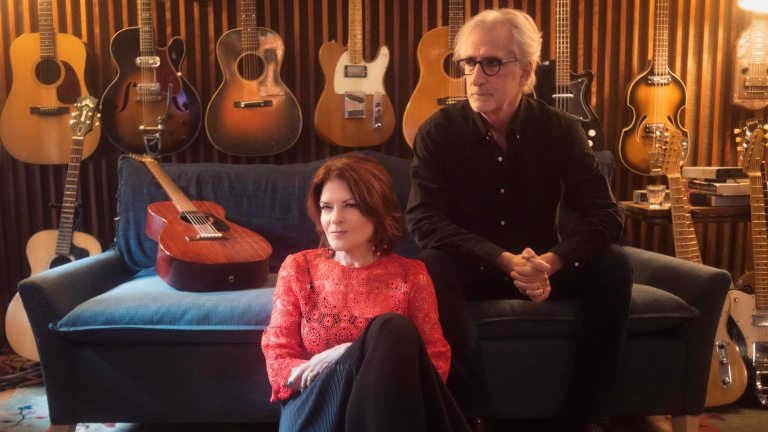 Man and woman sitting on a coach with guitars
