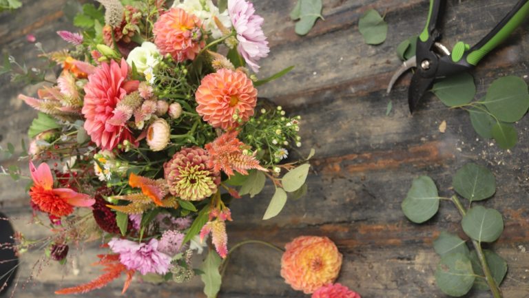 A floral arrangement being crafted on a wood table