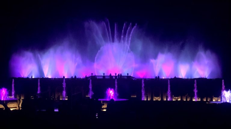 Large fountain display in pink and purple against a black night sky.