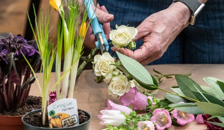 A person using scissors to shape a flower going into an arrangement.
