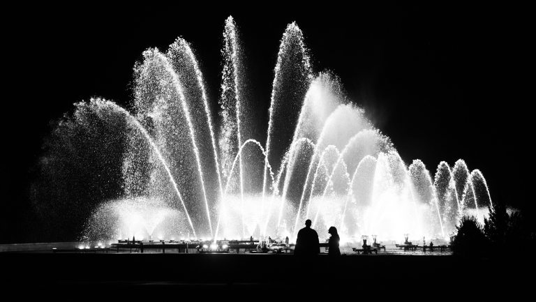 Large fountain display in black and white, with the silhouettes of two people off-center right.