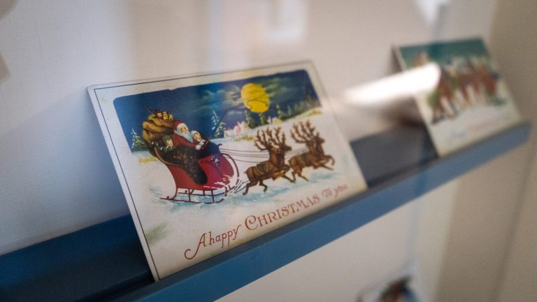 Two vintage Christmas cards on a blue ledge.