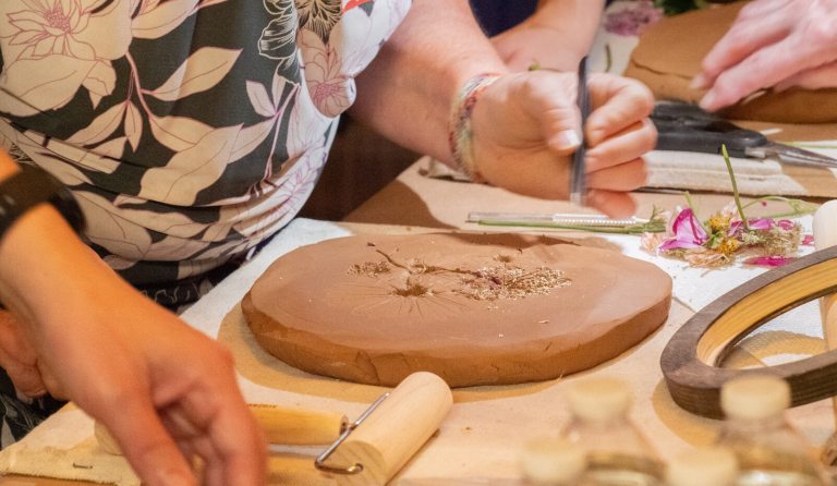 A person working with pressed flowers and clay.