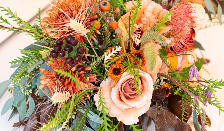 A floral arrangement in shaders of peach, featuring roses, wildflowers and other floral varieties.