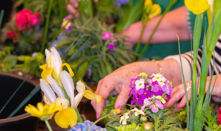 A person arranging a vibrant color floral display.