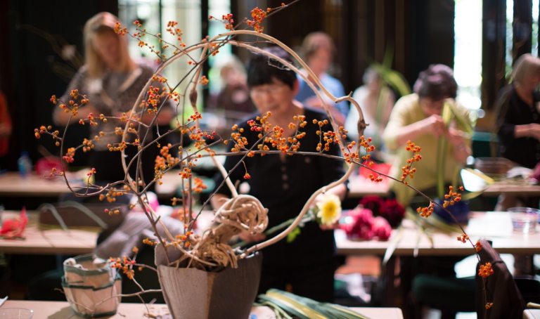 A person in a large room creating an Ikebana arrangement.