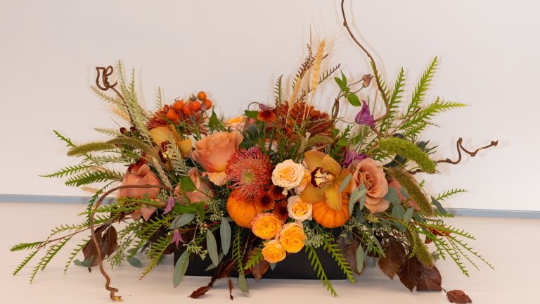 A autumn theme floral arrangement in oranges and yellows.