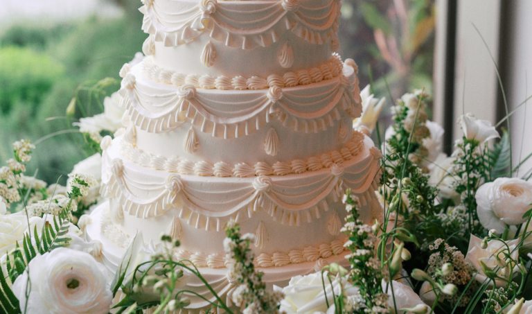 A white wedding cake set among white floral material.
