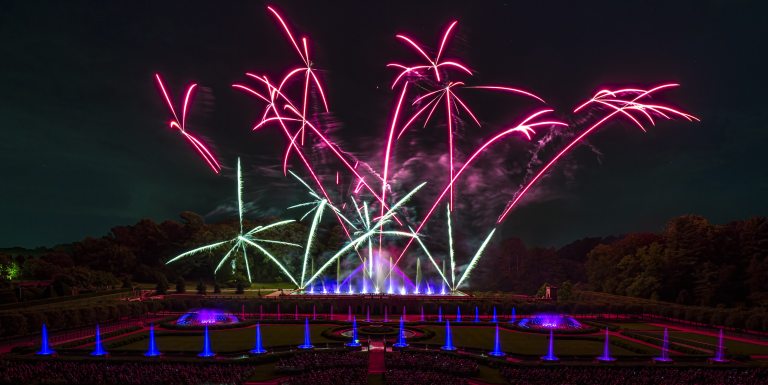 Shooting star fireworks in fuchsia with fountains in foreground.