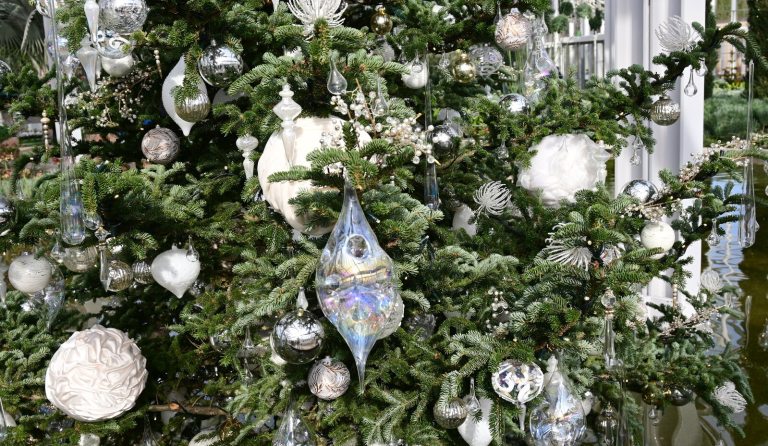 A close up of a decorated Christmas tree in while and silver ornaments.