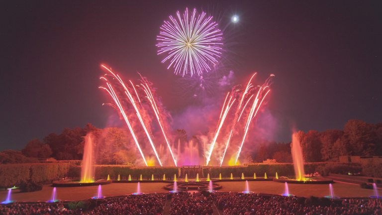Fountains and fireworks in hues of yellow, red, and violet, with angled fireworks mimicking fountains and framing a large round central fireburst.