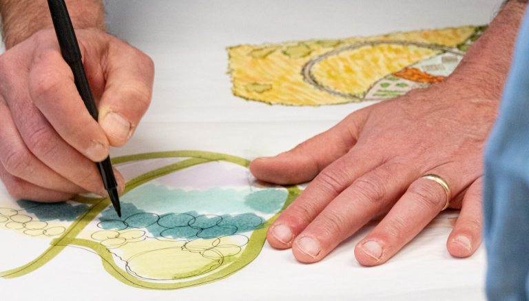 A person's hands on a illustration of a landscape design plan.