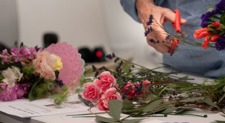 A person's hands holding floral material and clippers. 