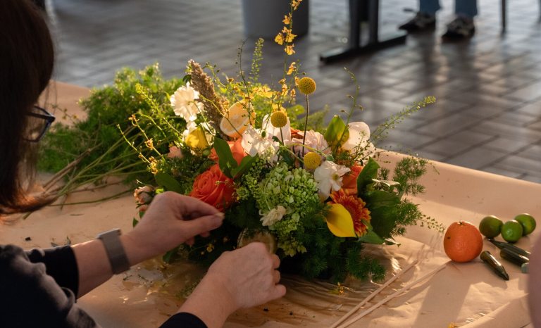 A person crafting a floral design in a white table.