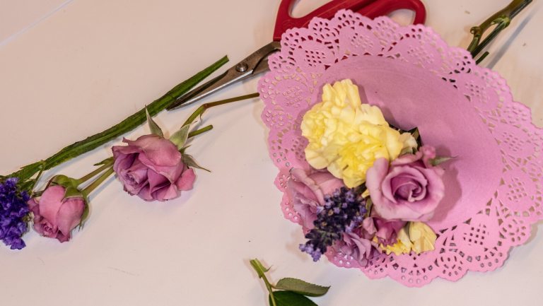 A small floral bouquet encased by a pink doily.