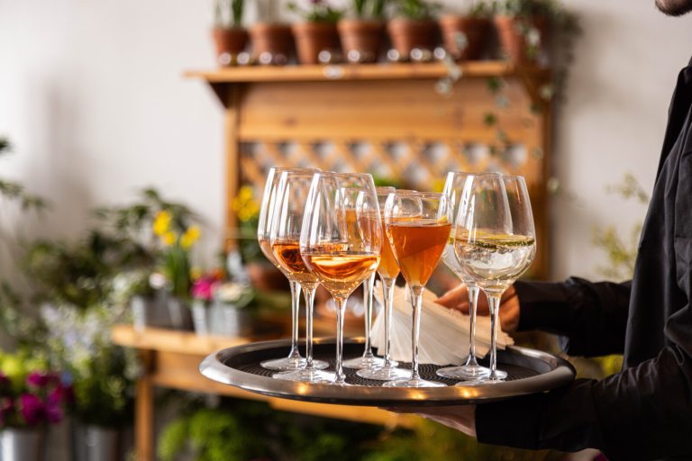 A tray of wine glasses, being carried on a tray.