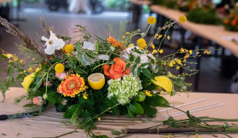 A finished floral tablescape, with yellow, orange and white blooms. 