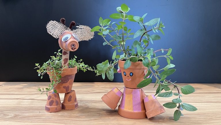 Giraffe and person crafted out of small terracotta pots planted with herbs