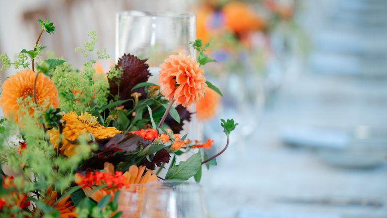 Closeup of bright fall flowers amid table settings.