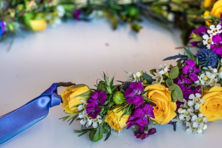 A floral crown being crafted out of purple, yellow, and white flowers. 