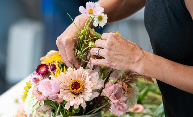 A person arranging a vibrant color floral display.