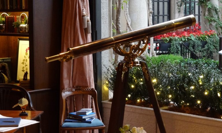 A telescope aimed outside a window in an office study. 
