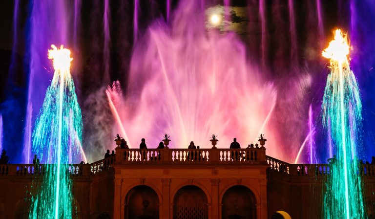 A fountain show at Longwood featuring uplight fountains in pink, blue, and teal lights. 