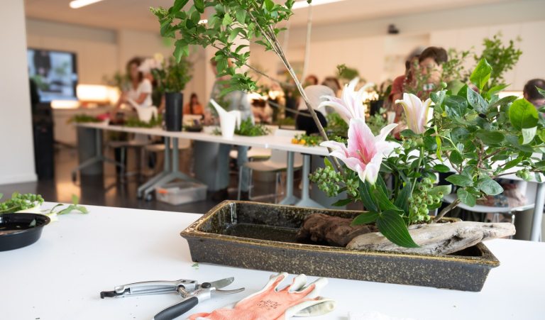 An ikebana creation, in a shallow gray tray, in a classroom.