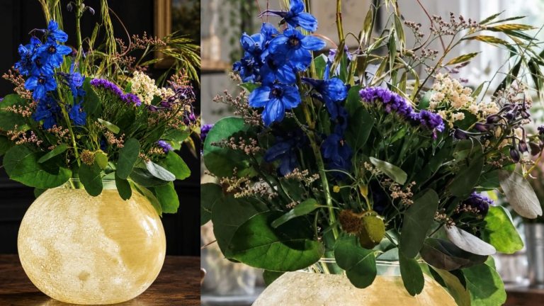 A floral arrangement with an illuminate moon vase and blue and purple flowers.