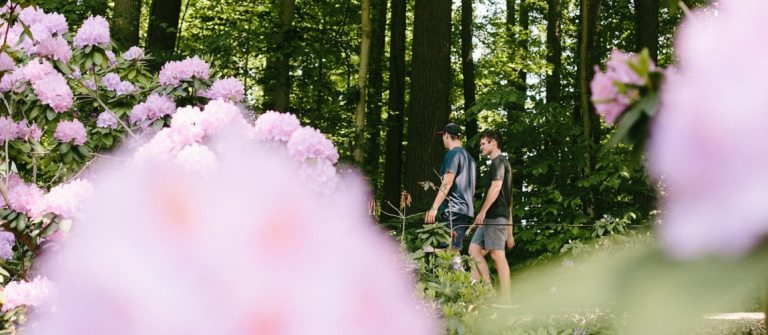 two people walking outdoors among pink blooming shrubs