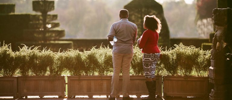 two people overlooking a topiary garden at sunset