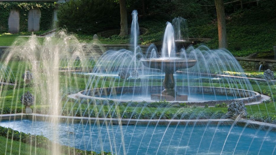 an outdoor fountain garden with blue basins and green grass