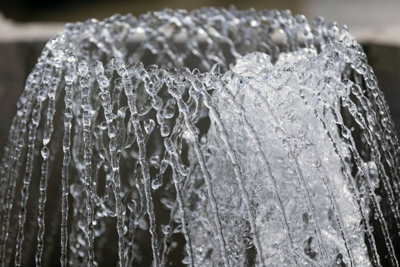A fountain of small water lines form an arch, basket-like design 