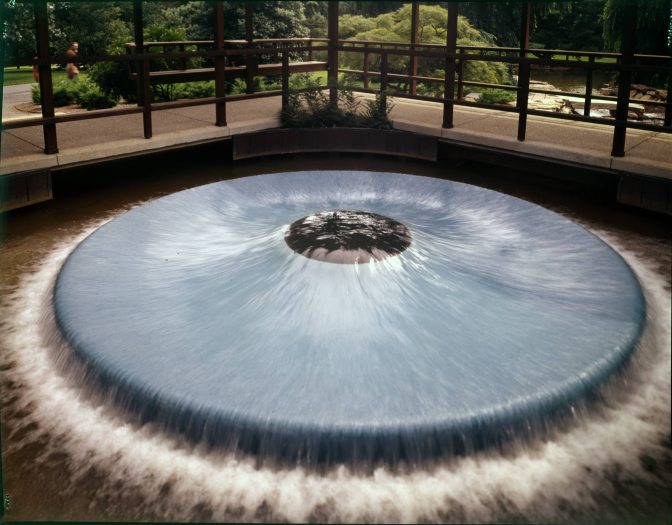 Water flows out of the middle of a circular blue ledge in a pool of water