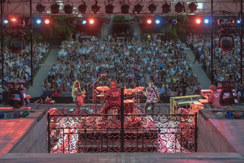 View of a crowd enjoying a live concert from upstage behind the performers.