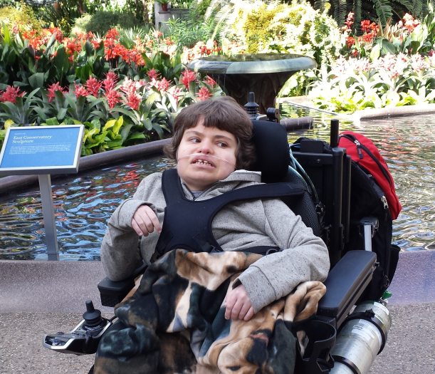 person in a wheelchair with flowers behind them