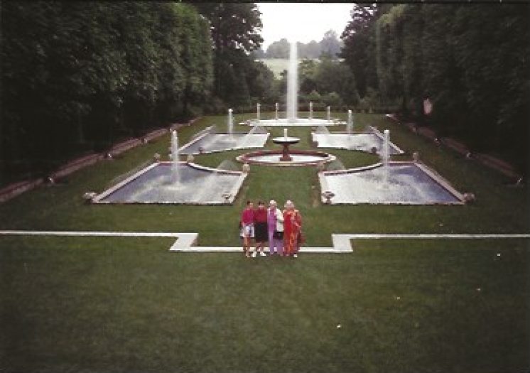 4 people standing in a garden in front of fountains