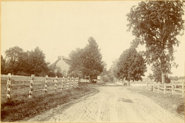 black and white image of an old house in the background with fencing