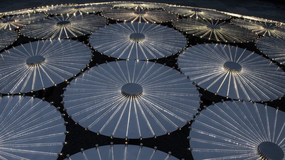 an array of large reflective discs are lit up along their radial lines