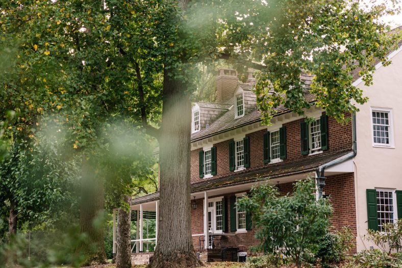 A large brick house stands among green trees