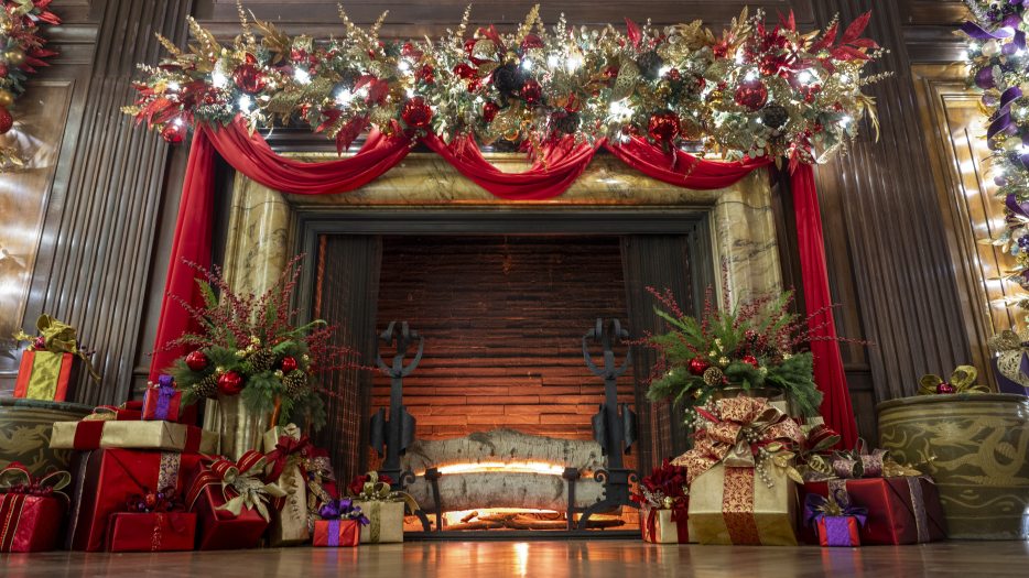 mantle and fireplace decked with red fabric swags and gilded decorations