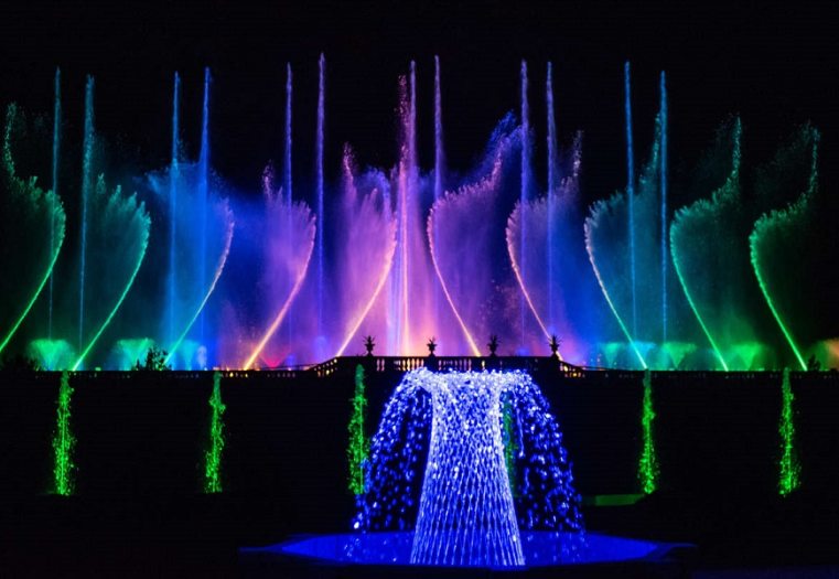 a wall of fountains that glow colors of green, blue, purple, and pink 