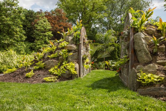 landscaped mounds of rocks and large stone gates open into a garden dominated by the foliage of palms and elephant's-ear-plants