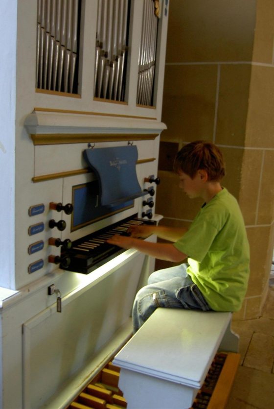 child sitting at organ playing keys