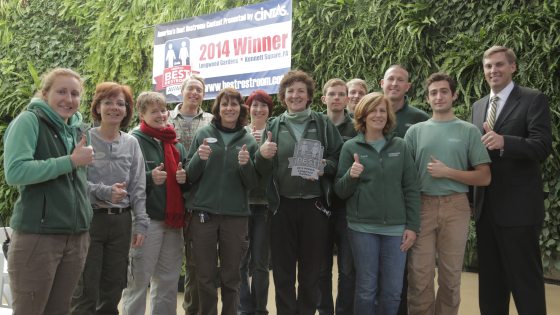 Longwood employees hold Best Restroom award in front of the Green Wall