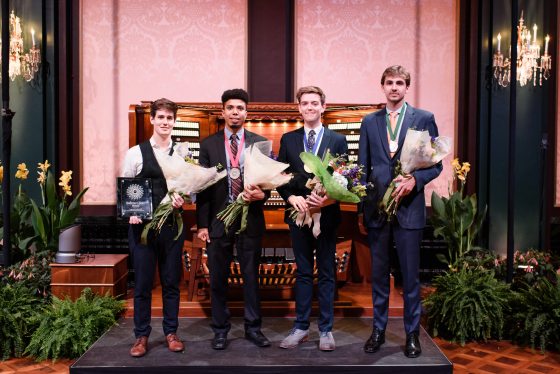 Competitors hold flowers and plaques in front of Longwood Organ